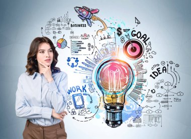 Mavi gömlekli düşünceli iş kadını elinde ampul, roket fırlatma, çark, iş, plan, duvarda takım çalışması olan çizimin yanında duruyor. Hayal gücü kavramı ve yaratıcı fikirler için ilham.