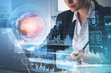 Resmi takım elbiseli iş kadını dizüstü bilgisayarın önünde not alıyor. Hud ile dijital arayüz asma kilit, veri depolama, bar ve pasta diyagramı, ön planda sanal dünya. Gelecekteki teknoloji kavramı