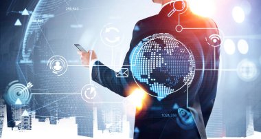 Resmi takım elbiseli bir iş adamı akıllı telefondan mesaj yazıyor. Arka planda Singapur ve New York gökdelenleri var. Sanal dünyanın hologramıyla dijital arayüz ve ön planda roket fırlatma