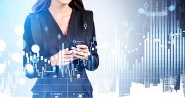 Ofisteki kadın akıllı telefon kullanıyor, borsa değişikliklerini analiz ediyor. Mavi çizgilerin, şamdanların ve bulanık gökdelenlerin çift pozlu hologramı. Çevrimiçi ticaret ve teknoloji kavramı