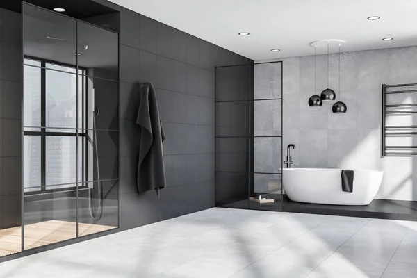 Corner of grey and black bathroom interior with oval bathtub, pendant lamps, steel details, framed glass partitions and shower cabin. Tiles. Modern apartment design concept. 3d rendering