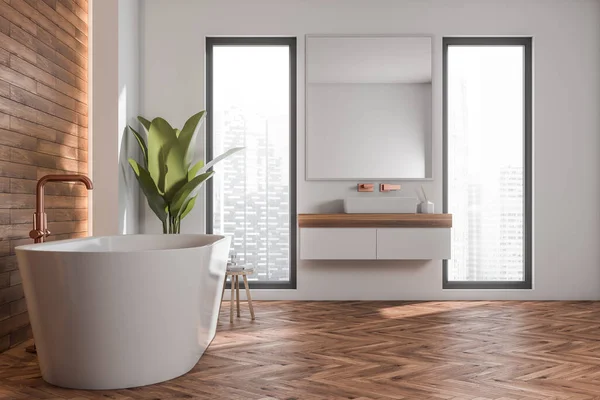Bathroom interior with oval white bathtub, two narrow windows, floating vanity and copper faucets. Concept of modern apartment design, using wood-look tiled wall and parquet style floor. 3d rendering