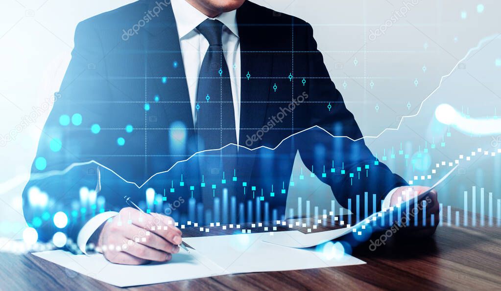 Office man in suit with pen and paper in hands, signing a contract. Double exposure of growing stock market candlesticks. Concept of financial contract