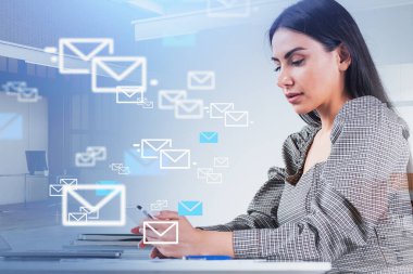 Gri elbiseli iş kadını akıllı telefondan mesaj yazıyor. Çalışma masası, dizüstü bilgisayarı ve arka planda not defterleri olan bir ofis. Sosyal medya, iletişim ve ağ kavramı