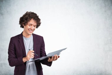 Ofisteki adam elinde kalemle gülümsüyor, günlük kıyafetlerle not alıyor. Pano ile mutlu bir yönetici, iş notlarını okuyor. Boşluk duvarını kopyala, iş işçisi kavramı