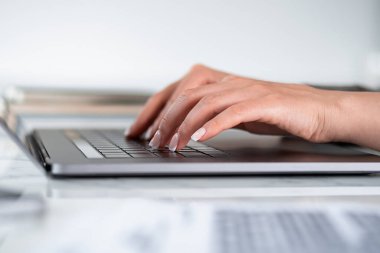 Masada dizüstü bilgisayarı olan bir iş kadını, dizüstü bilgisayarda yazan parmaklar, yakın çekim. Ofiste çalışan bir yönetici. Sekreter ve yönetici kavramı