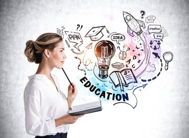 Beyaz tişörtlü çekici genç bir kadın elinde bir defter ve çenesinde kalemle yeni bir iş kurmak için eğitim hakkında kafa yoruyor. Arka planda beton duvar ve eğitim çizimleri