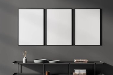 Siyah askılı, minimalist dekorasyonlu, seramik tabaklı, sazlık difüzörlü karanlık bir sanat odası. Üç boş çerçeve satırı, üç boyutlu görüntüleme