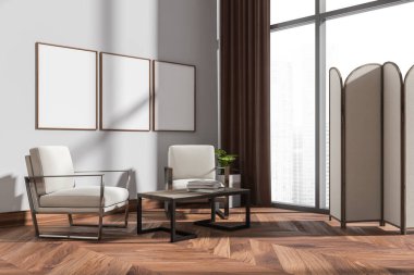 İki koltuklu dinlenme odası ve kitaplı kahve masası, kenar manzaralı, şehir manzaralı bej panelli pencere. Duvardaki üç boş tuval çerçevesi, üç boyutlu görüntüleme