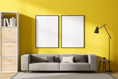 İçerisi kanepe ve kitaplarla dolu ahşap bir raf parke zemininde dekorasyon halısı olan bir sehpa. Sarı duvardaki iki boş tuval, üç boyutlu.