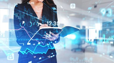 Ofisteki kadın iş belgelerine yazı yazıyor. Dijital arayüzün, bar tablosunun ve borsa verilerinin mavi simgeleri. Mali analiz ve danışman kavramı