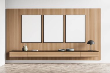 Sanat odası içi ahşap komodinli kitaplar, seramik vazo ve tabaklar parke zeminli misafir odası. Üç model çerçeve ahşap duvarda, üç boyutlu.