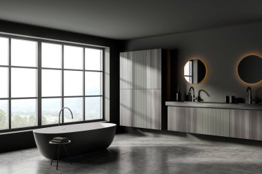 Küvetli gri banyo ve havlularla dolu masa, iki lavabo ve arka lambalı ayrı yuvarlak aynalar, siyah ahşap raf, kırsal alanda gri beton zemin ve pencere, 3D