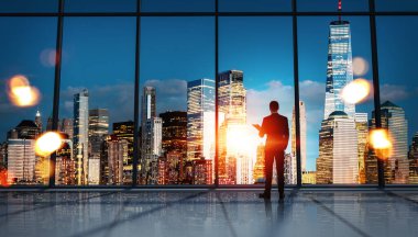 New York gökdelenlerinin gece panolarına bakan gizli bir ofis çalışanı. Bokeh ışıkları var. Gelecek planları ve patron kavramı