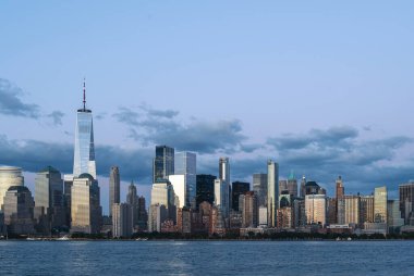 New York gökdelenlerinin ışıkları, akşamları ofis binaları, finans şirketleri. Manhattan gökdelenleri bulutlu gökyüzü altında, Dünya Ticaret Merkezi. İş gezisi kavramı