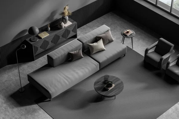 Top view on dark living room interior with large grey sofa, two cozy armchairs, carpet, pillows, panoramic window, sideboard, concrete floor. Concept of comfortable place for meeting. 3d rendering