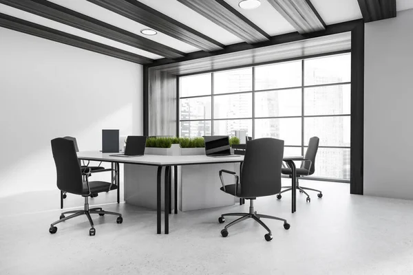 Corner view on dark office room interior with panoramic window, six laptops, comfortable armchairs, desks and concrete floor. Perfect place for meeting and work. Minimalist design. 3d rendering