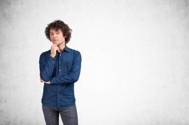 Kot gömlekli bir ofis çalışanı kameraya özenli ve düşünceli bir şekilde bakıyor. Planlar ve yeni fikirler üreten genç bir patron. Planlama kavramı. Boş gri beton arkaplan