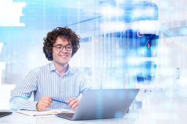 Resmi tişört giyen gülümseyen genç ve yakışıklı iş adamı online video konferans görüşmesi yapıyor. Arka planda şehir gökdeleni olan ofis işyeri. Finansal önx şeması, grafik ve çubuk diyagramı