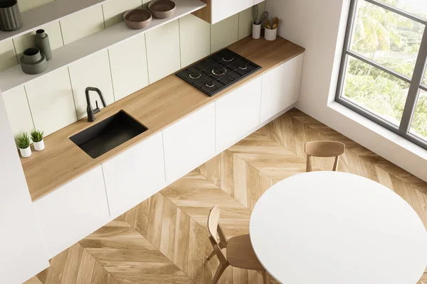 Top view of kitchen interior with round dining table, parquet floor, window, simplified white modular cabinet with light green backsplash and two open shelves. Concept of modern design. 3d rendering