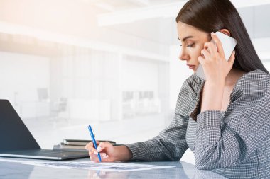 Ofisteki kadın telefonda konuşuyor, masada dizüstü bilgisayar ve kağıtlarla oturuyor. Finansal danışman arıyor ve bir sözleşme imzalıyor. Şirkette yönetici kavramı