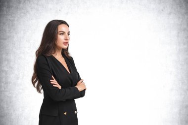 Siyah takım elbiseli patron kadın, kollarını kavuşturup gülümsüyor, kendinden emin görünüyor. Boşluk boş gri duvarı kopyala. Girişim ve iş planı kavramı