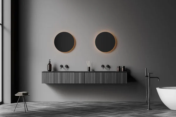 Dark bathroom interior with two round mirrors, panoramic window, sinks, bathtub, grey walls and oak wooden parquet floor. Concept of hygienic and spa procedures. 3d rendering