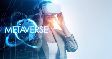 Resmi takım elbiseli iş kadını video kaskı giyiyor ve tutuyor. Geometrik şekillerle dijital arayüz ve ön planda çizgi bağlantısı. Dünya ve metaevren hologramı. Sanal gerçeklik kavramı