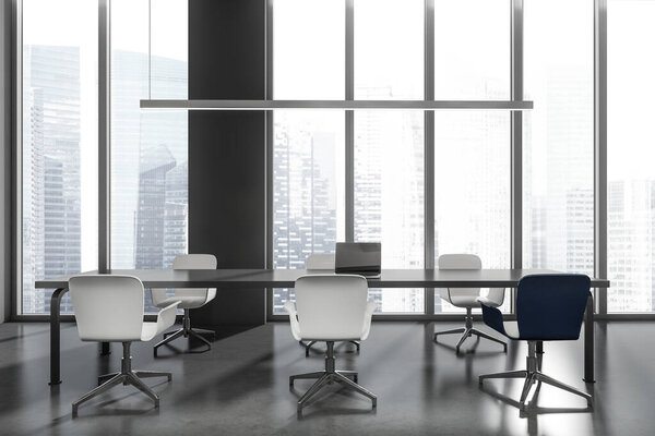 Dark industrial office interior with armchairs, laptop on black table, grey concrete floor. Office space with device, panoramic window with Singapore skyscrapers, 3D rendering