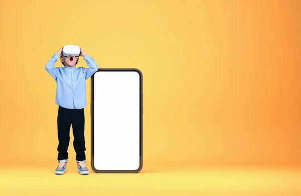 仮想現実の眼鏡をかけた小さな子供だ スマートフォンのコピースペース画面 黄色の背景をモック メタパスと新しいデバイスの概念 — ストック写真