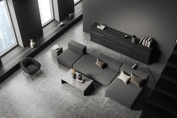 Top view of dark living room interior with sofa and armchair, coffee table and drawer with decoration, grey concrete floor. Window on Singapore city view. 3D rendering
