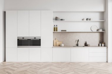 Parlak mutfak odasının önü çift fırın, dolap, lavabo, yağlı raflar, çanak çömlek, ahşap zemin, beyaz duvar. Minimalist tasarım kavramı. Yaratıcı fikir için yer var. 3d oluşturma