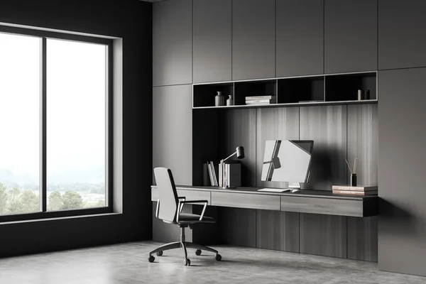 Dark workplace interior with armchair and pc computer, books and decoration, grey concrete floor. Home office with panoramic window on countryside view. 3D rendering