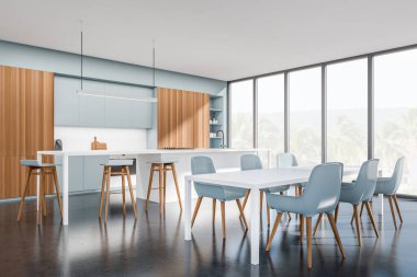 White kitchen interior with blue chairs and dining table and countertop on dark concrete floor, side view, eating space with kitchenware, panoramic window on countryside. 3D rendering