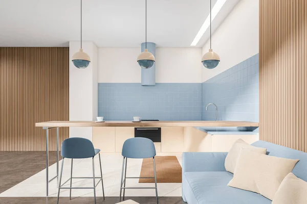 Blue kitchen interior with sofa and two bar chairs, wooden countertop. Chill zone and eating area with modern furniture in minimalist studio. 3D rendering