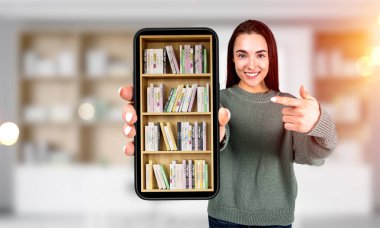 Mutlu bakışlı genç bir kadın, mobil uygulamalı dijital kütüphane telefonuna parmak işareti, rafta kitapları olan bulanık bir arka plan. Çevrimiçi eğitim kavramı