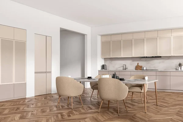 Beige kitchen interior with armchairs and eating table on hardwood floor, side view. Kitchenware, sink and fridge. Open space cooking area. 3D rendering