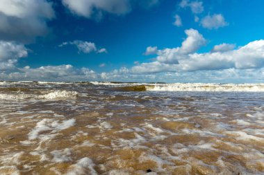 Deniz dalgalarının kıyıya vurduğu güzel deniz manzarası ve patlayan güzel mavi gökyüzü ve denizin üzerinde beyaz bulutlar, Vidzeme kayalık kıyı kıyısı, Salacgriva kırsal bölgesi, Letonya