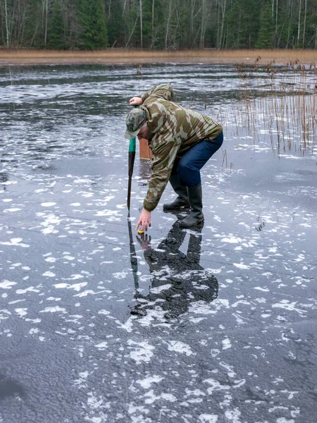 Vinterfiskare Kontrollerar Isens Styrka Och Tjocklek Bländning Isytan Nakna Trädsiluetter — Stockfoto