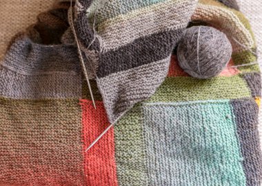 Yün yumağı ve ahşap örgü iğneleri, örülmüş arka plan ve doku, el yapımı, örgü desenli arka plan.