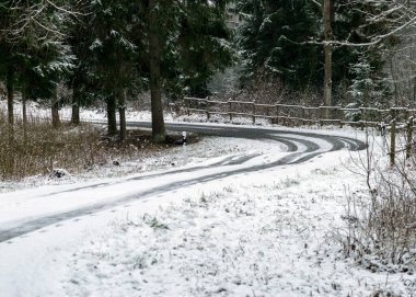 Kış manzarası karlı bir kır yolu ve yol kenarında karla kaplı ağaçlarla, kış günü