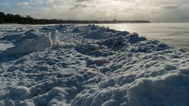 Deniz kenarındaki kış manzarası, deniz kenarındaki karlı buz parçaları, parlayan beyaz kar tabakasıyla kaplı kumullar, kış.