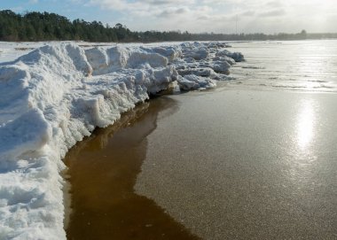 Deniz kenarındaki kış manzarası, karlı, deniz kıyısındaki ilginç buz şekilleri, beyaz bir kar tabakasıyla kaplı kumullar, kış