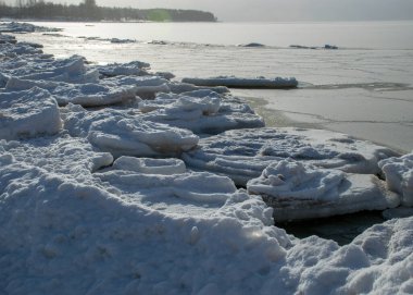 Deniz kenarındaki kış manzarası, karlı, deniz kıyısındaki ilginç buz şekilleri, beyaz bir kar tabakasıyla kaplı kumullar, kış
