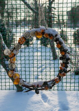 Tatilden sonra Noel süslemeleri, bahçede karla kaplı hasır süslemeler, yeşil ağ desenli arka plan.