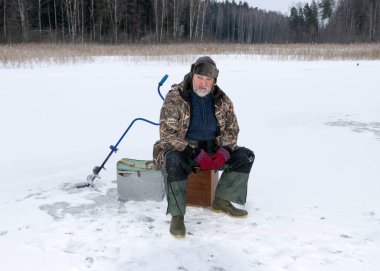 Güneşli bir günde buz nehrinin üzerindeki kış manzarası. Kış sporları, balıkçı gölde buzda balık tutmayı, gölde kış balıkçılığını sever..