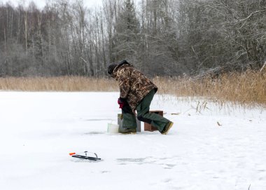 Güneşli bir günde buz nehrinin üzerindeki kış manzarası. Kış sporları, balıkçı gölde buzda balık tutmayı, gölde kış balıkçılığını sever..