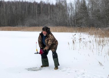 Güneşli bir günde buz nehrinin üzerindeki kış manzarası. Kış sporları, balıkçı gölde buzda balık tutmayı, gölde kış balıkçılığını sever..