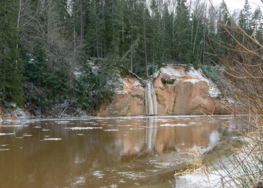 İlkbaharın başlarında nehir manzarası, kumtaşı çıkıntısı, suda buz küpleri, karşı kıyıdan nehir kıyısı, Erglu kayalıkları, Gauja nehri, Cesis, Letonya