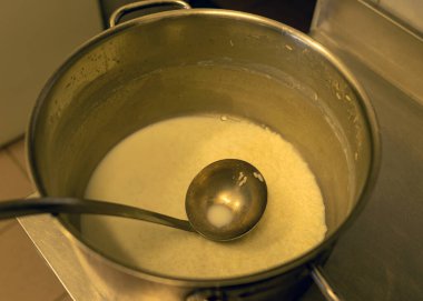 Ocağın üstünde süt çorbası, okul mutfağı, yemek pişirme konsepti, metal mutfak tenceresi olan metal kap.